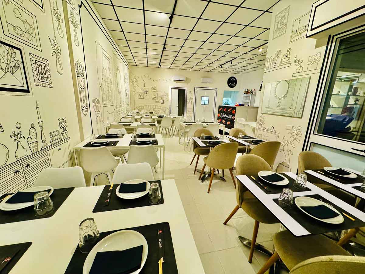 Sala del ristorante Black & White con illustrazioni a inchiostro sulle pareti e soffitto a griglia